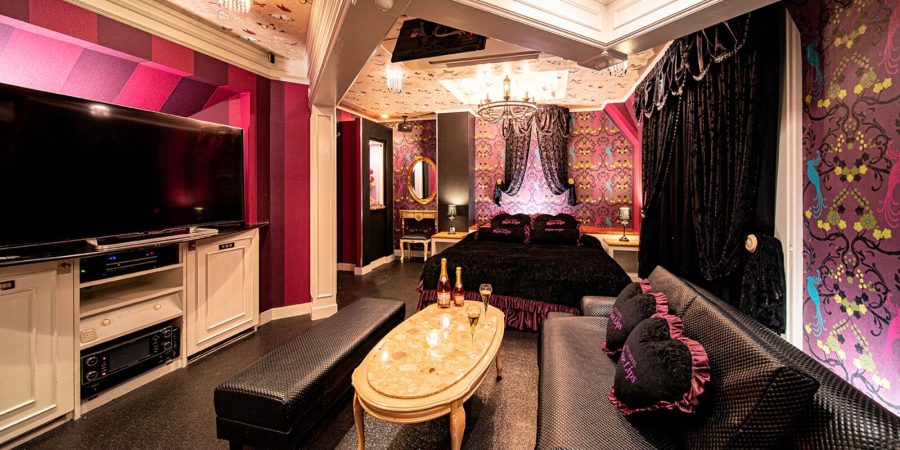 Pink and black themed room at Hotel Rose Lips Tsuruhashi with a large TV, sofa and low table