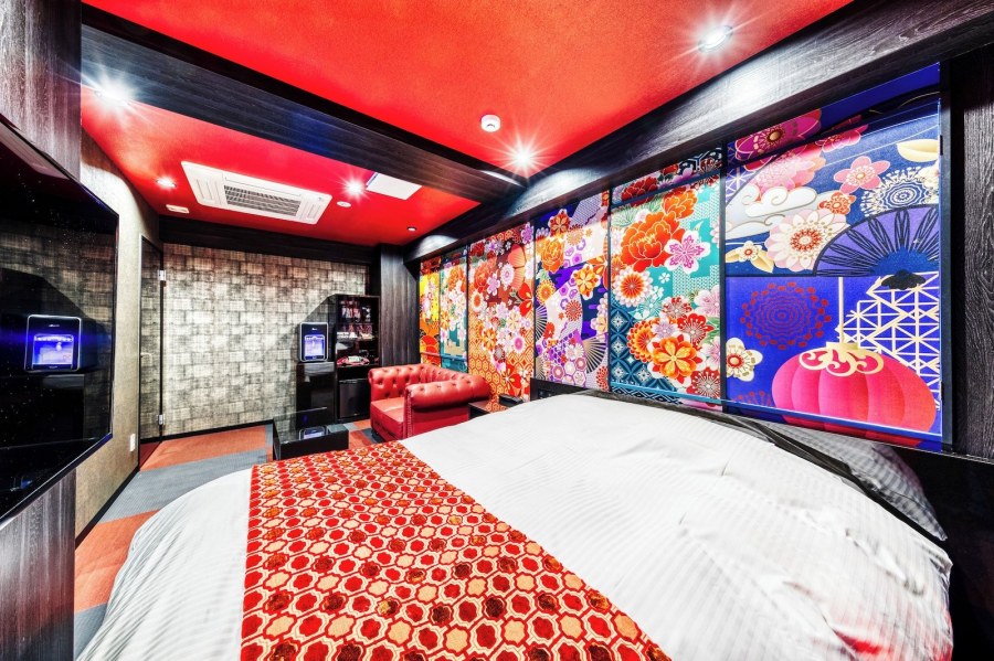 Hotel room at Hotel Lotus Umeda with a red ceiling, colourful Japanese-pattern wall panels and a red leather sofa